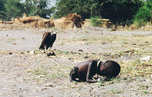 Et utmagra barn i Sudan ved sida av en gribb. Foto. 