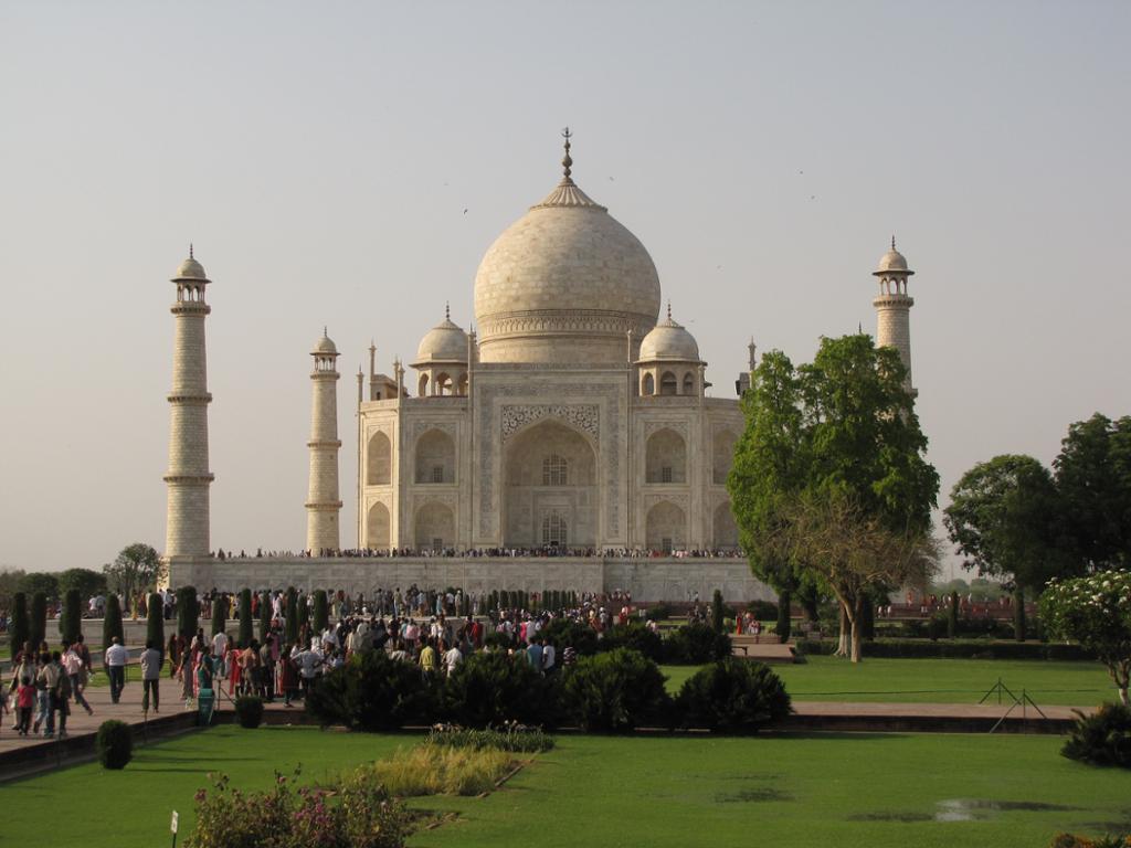 Photo: We see the Taj Mahal, which is a mausoleum made of white marble. We see many people outside the building. 
