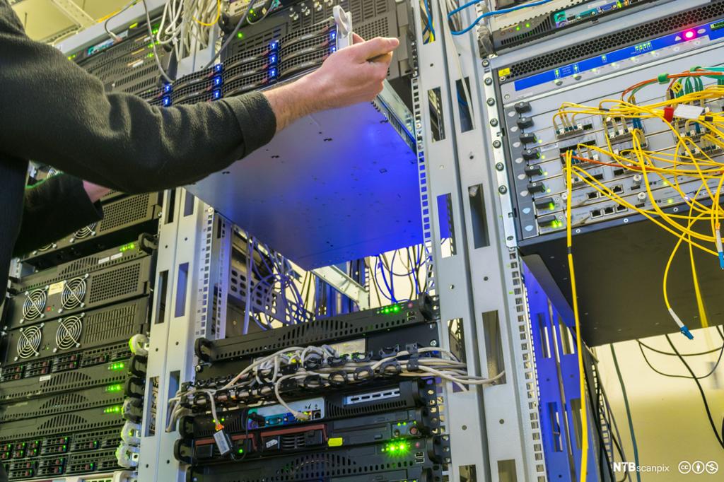 Teknikker monterer en server inn i et rack skap. Foto.