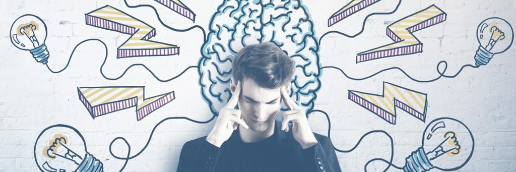 Person som holder seg til hodet og står foran en vegg med tegninger av en hjerne med lyspærer og lyn rundt. Foto. 