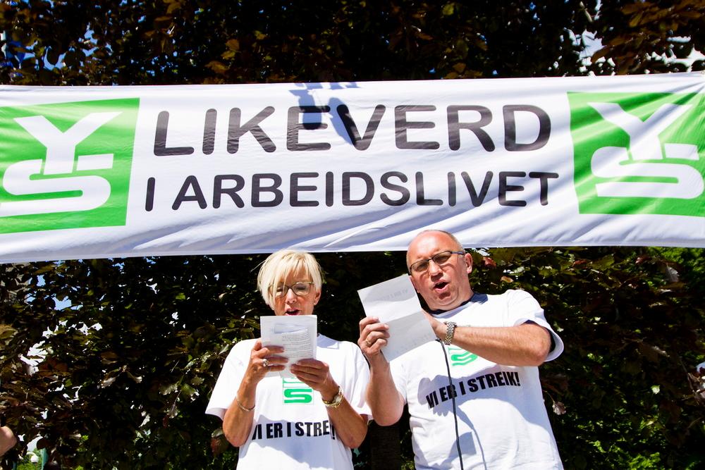 Arbeidstakerorganisasjonen YS i streik. To representanter med et banner som sier "Likeverd i arbeidslivet". Foto. 