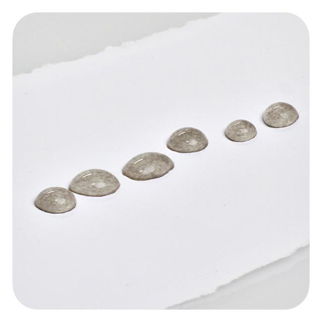 Seks dråper sølvnitrat plassert etter hverandre på et stykke papir. Foto.