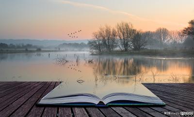 Oppslått bok som ligger på ei brygge ved et stille vann. Deler av boka ser ut til å gli over i selve landskapet. Manipulert foto.