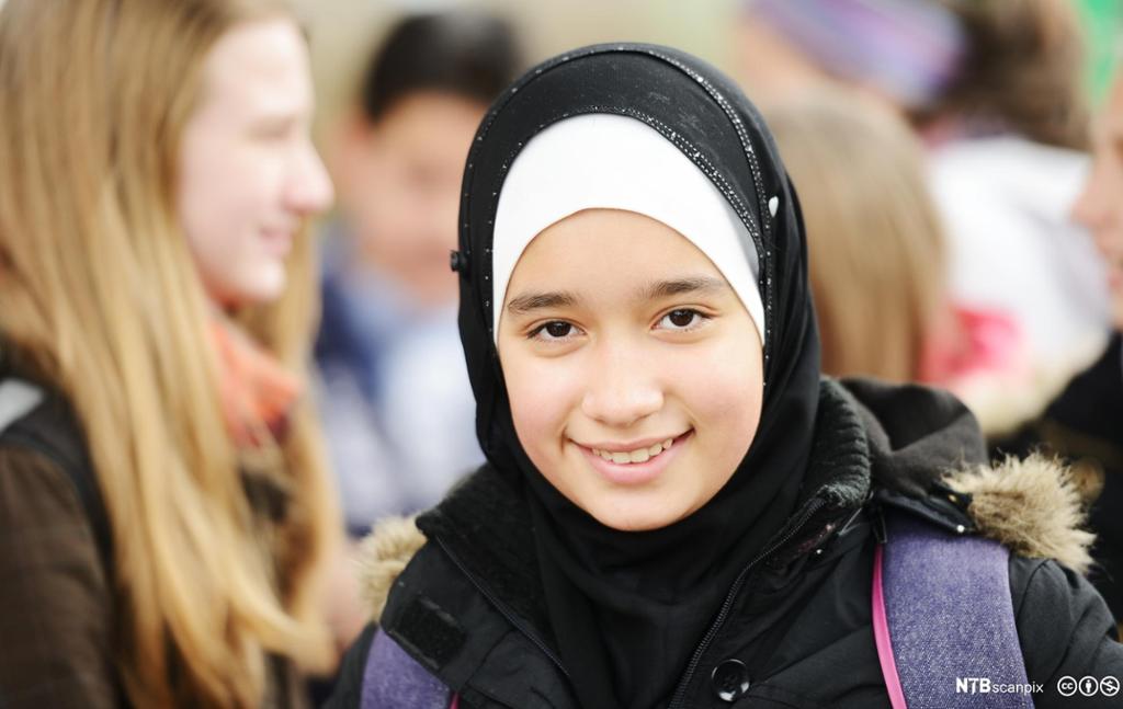 Ung muslimsk elev med hijab blant ikkje-muslimar. Foto.