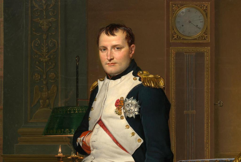 Napoleon i uniform i kontoret sitt. Han ser mot betrakteren og har handa karakteristisk stukke inn i jakka framme. Jakka er utstyrt med medaljar og gull på skuldrene. Måleri. 