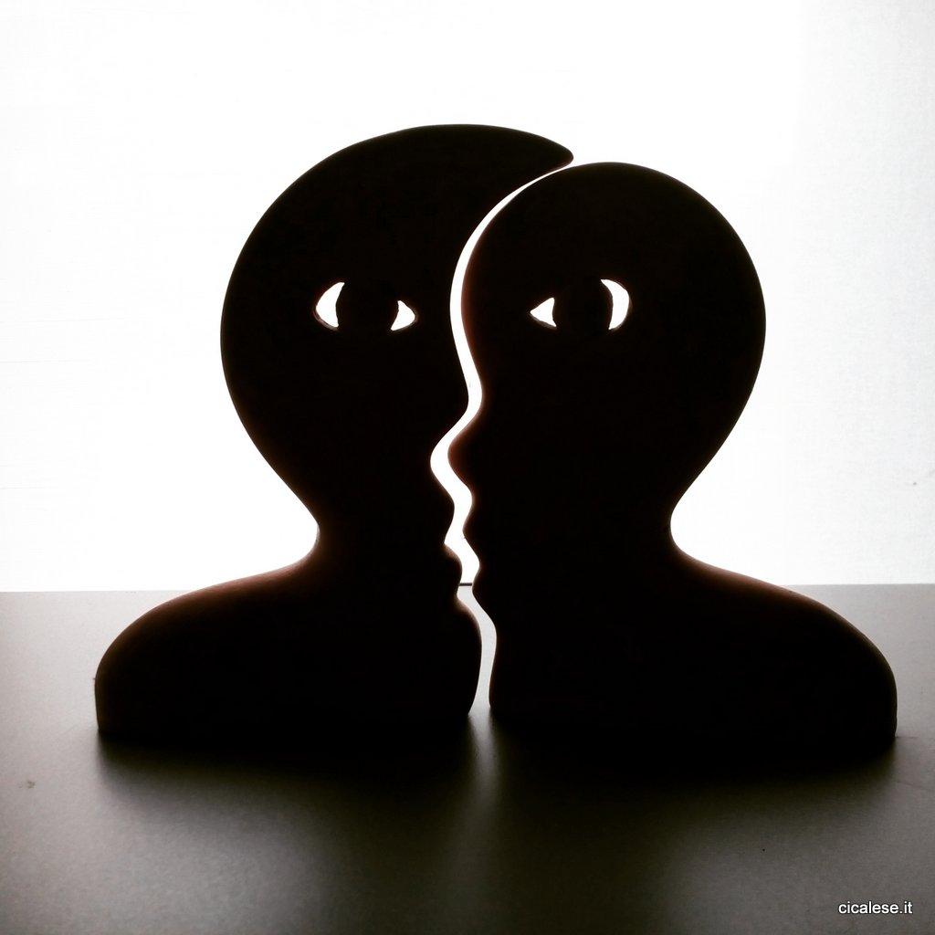 A black and white illustration of an art piece showing two faces that are intertwined with each other. Both faces are black while the background is white. Illustration.