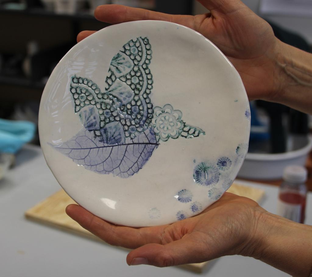 Hvitt keramikkfat med blått og grønt fuglemotiv. Foto.