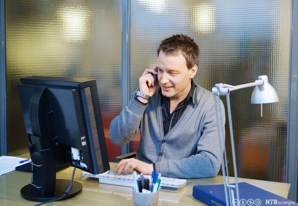 Mann som snakker i telefonen på et kontor. Foto.
