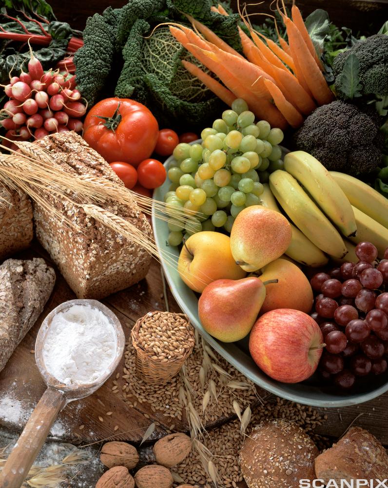 Forskjellige matvarer: mjøl, korn, valnøtter, grovbrød, reddik, kål, gulrøter, brokkoli, blå og grøne druer, eple, banan. Foto.