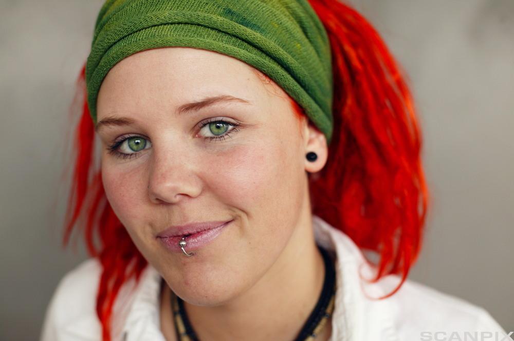 Jente med raudt hår, grønt hårbånd og piercing. Foto.