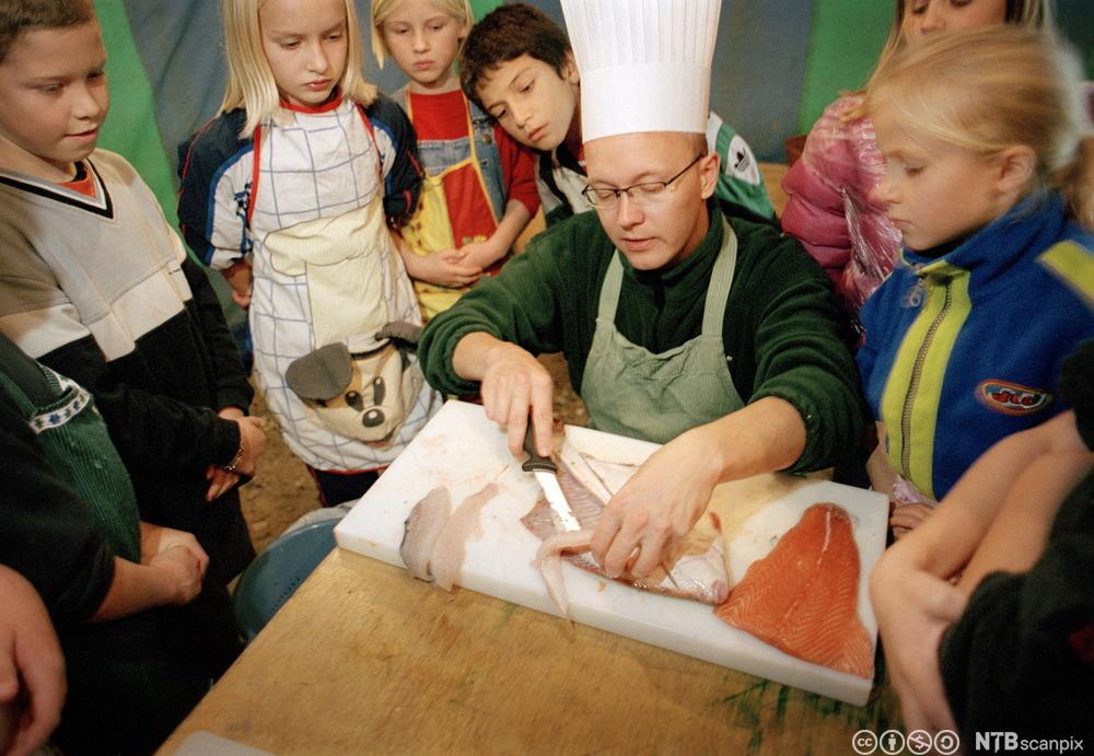 Kokk viser barn hvordan man renser fisk