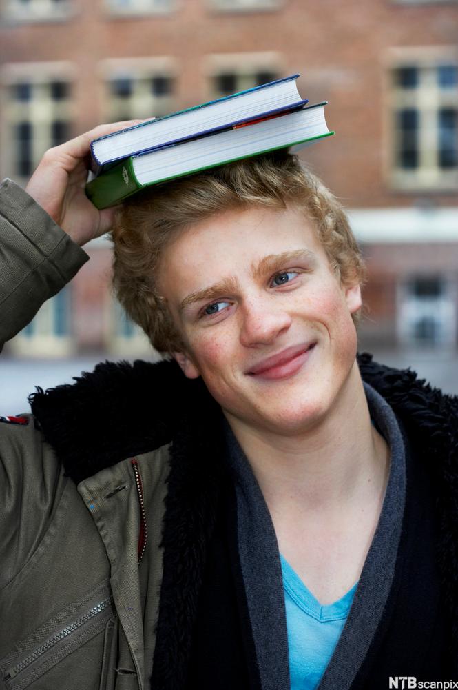 Gutt med bøker på hodet. Foto.