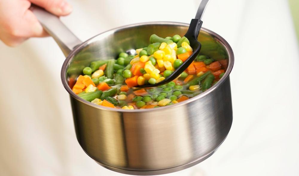 En kokk holder en kjele med grønnsaksuppe. Foto.