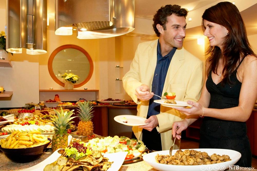 Bilde av et par som forsyner seg fra lunsjbuffeten på et hotell. Foto.