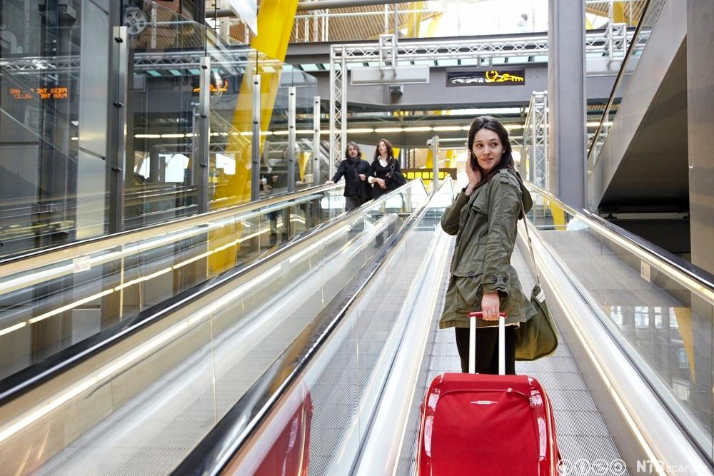 Ung kvinne med rød koffert. Foto.