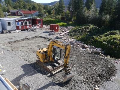 Gravemaskin klargjør byggetomt. Foto.