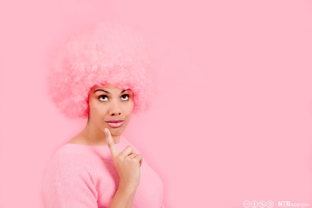 Kvinne iført rosa parykk tenker. Foto.