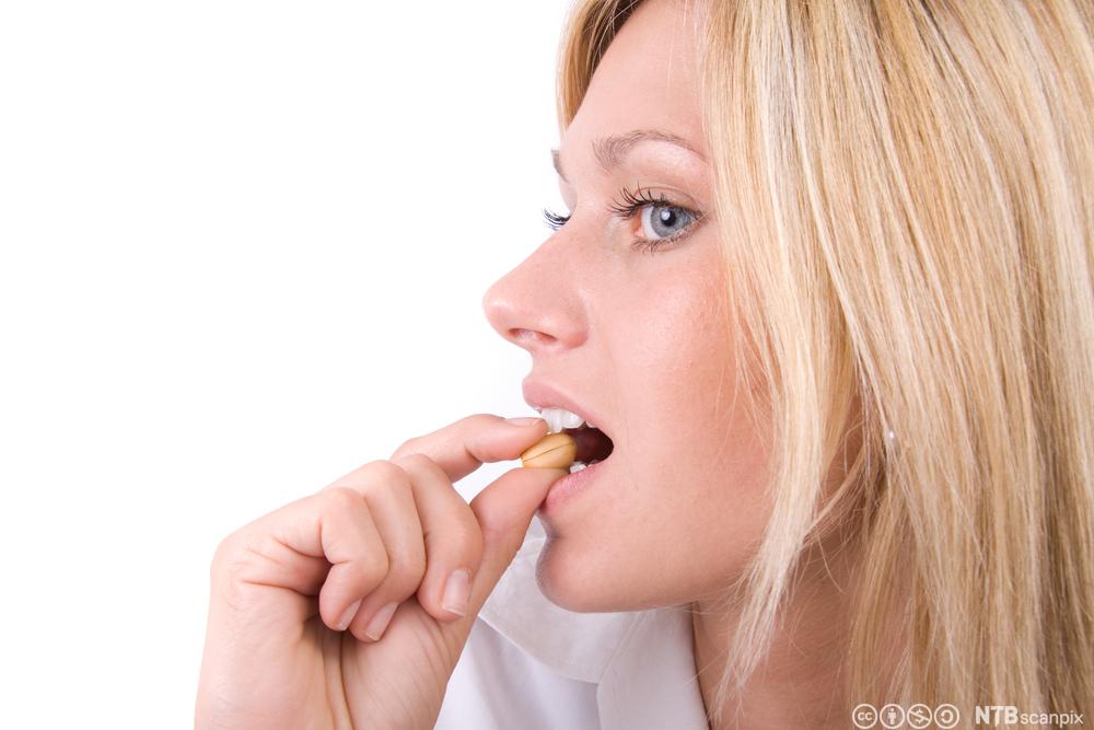 En dame som spiser en peanøtt. Foto.