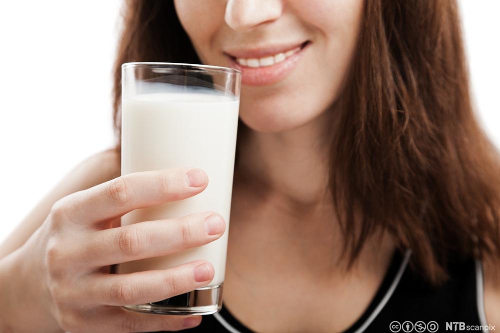 En dame holder et glass melk. Foto.