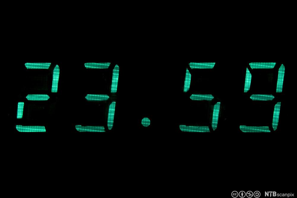 Digital klokke som viser klokkeslettet 23.59. Foto.