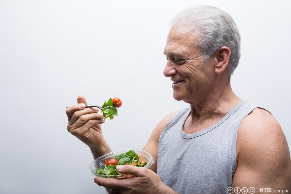 Mann som spiser salat. Foto