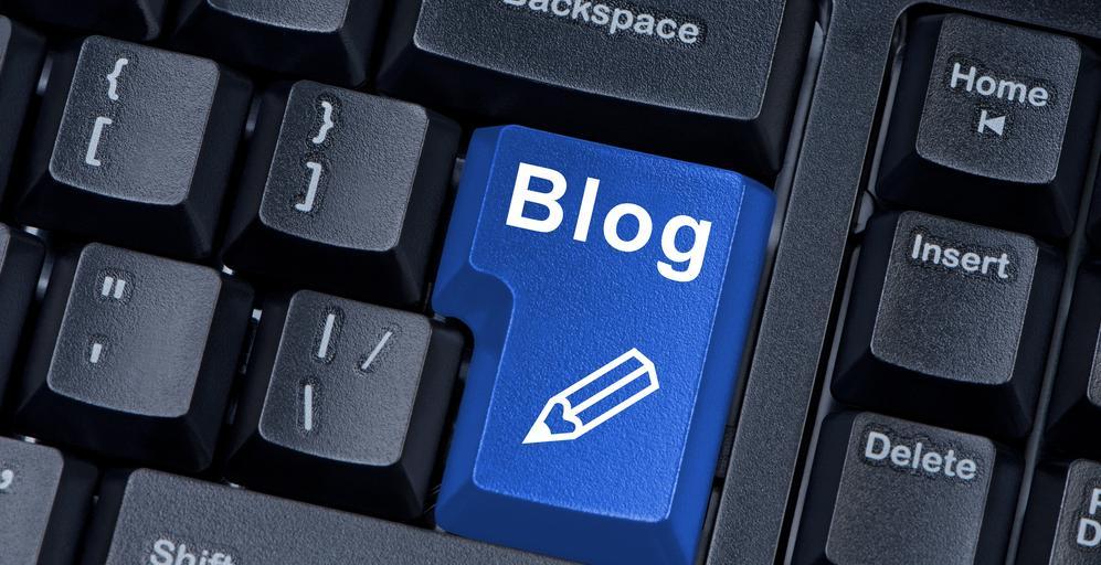 Foto med nærbilete av eit svart tastatur, der Enter-tasten er blå og har påtrykt teksten "Blog" og eit blyantsymbol.