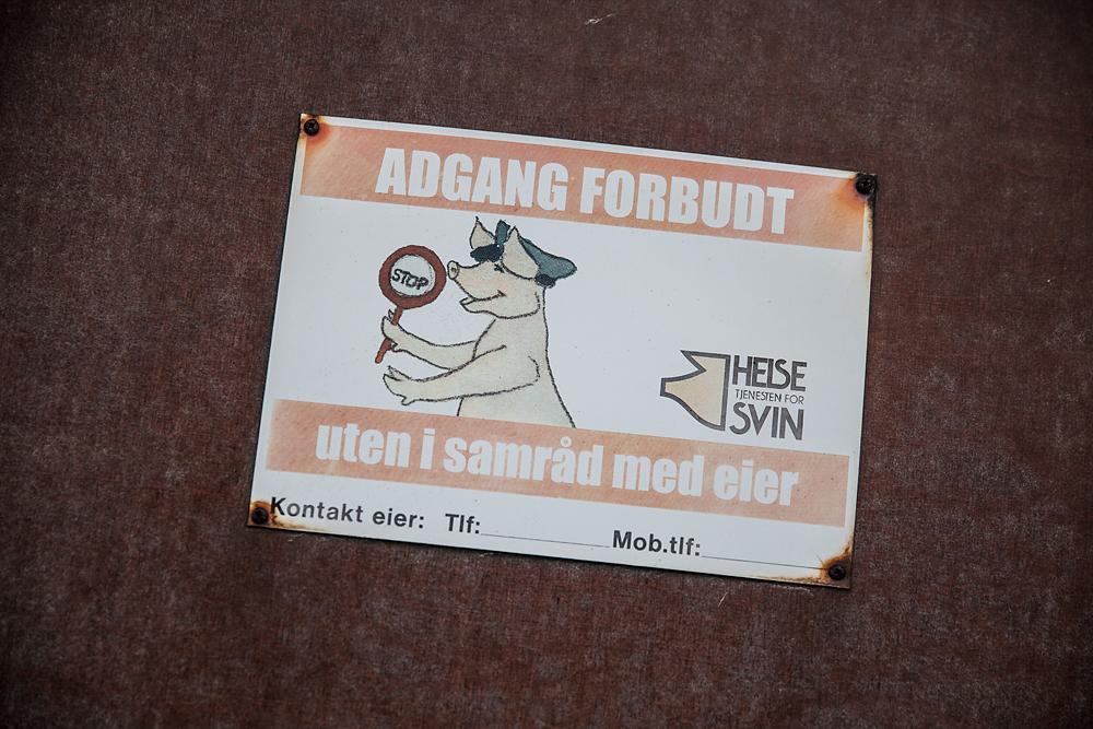 Advarselskilt med tegning av en gris med politilue og stopp-skilt og teksten "Adgang forbudt uten i samråd med eier". Foto.