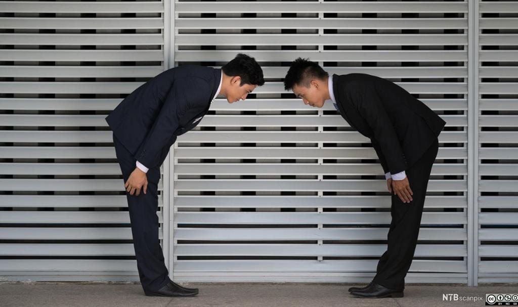 To japanske forretningsmenn hilser på hverandre ved å bukke dypt. Foto.