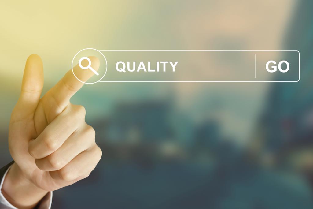 Ordet "kvalitet" er skrevet inn i et søkefelt på en skjerm, og en pekefinger trykker på søkeknappen. Illustrasjon.