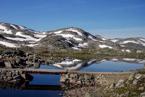 Norsk fjellandskap med bro over lite tjern. Foto.