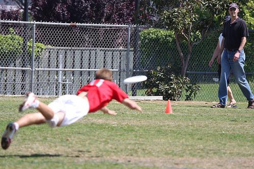 Spiller kaster seg etter frisbee i konkurranse. Foto.