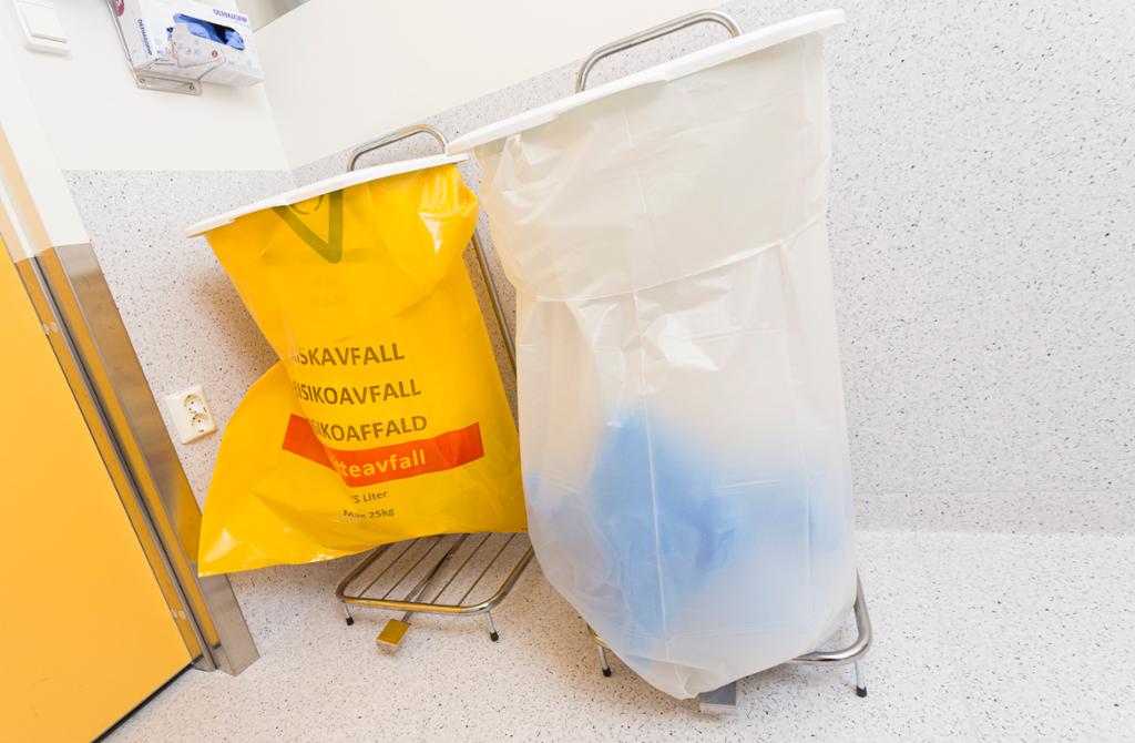 To søppelposer, en gul til risikoavfall og en gjennomsiktig uten merking. Foto.