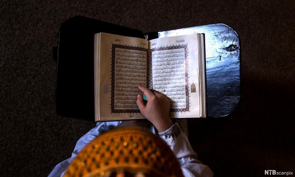En gutt leser i koranen og ber under Ramadan. Vi ser gutten ovenfra.  Foto. 