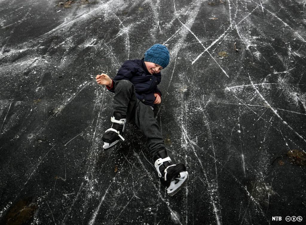 Gutt som har falt på isen mens han lærte å stå på skøyter. Foto. 