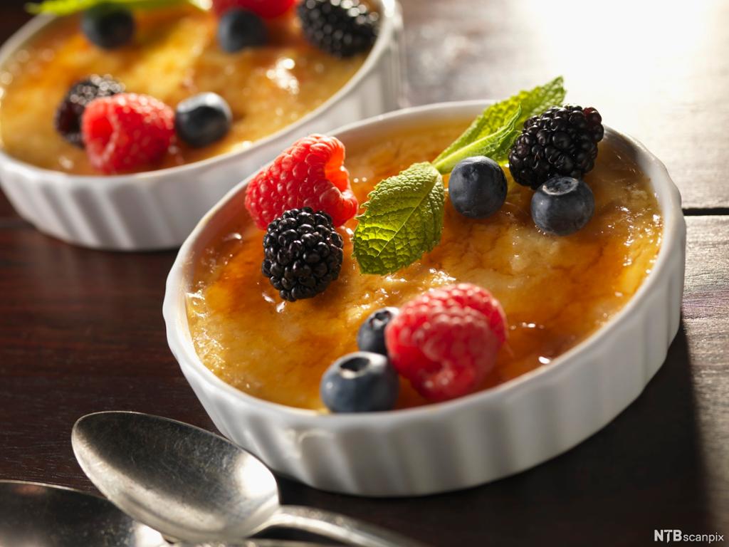 Crème brûlée i porsjonsskåler, pynta med blåbær, bjørnebær, bringebær og mynte. Foto.