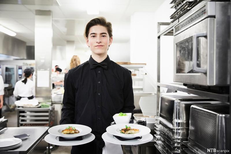 En servitør som holder to tallerkener. Foto.