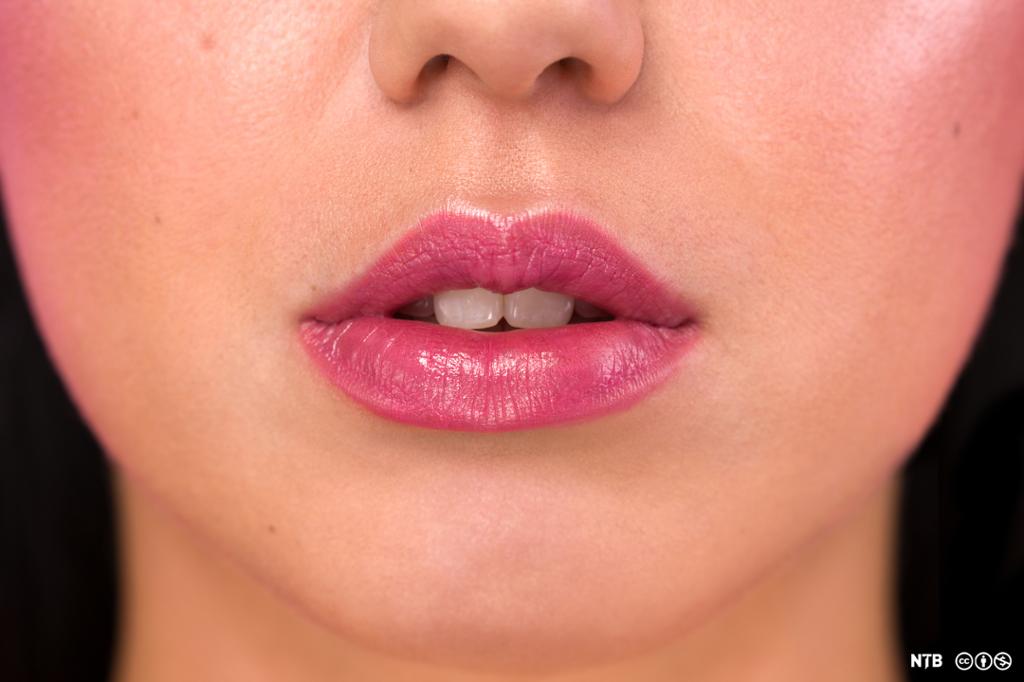 The lower half of a young woman's face. Her lips are paited and slightly parted. 