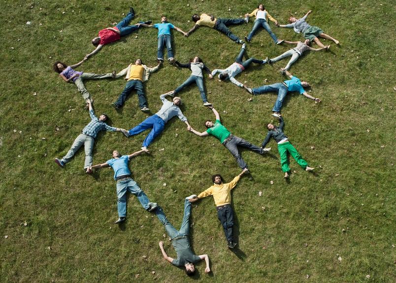 Mennesker som ligger i gresset i mønsteret av et hjerte. Foto.