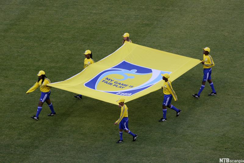 Flaggbærere bærer FIFAs Fair Play-flagg. Foto.