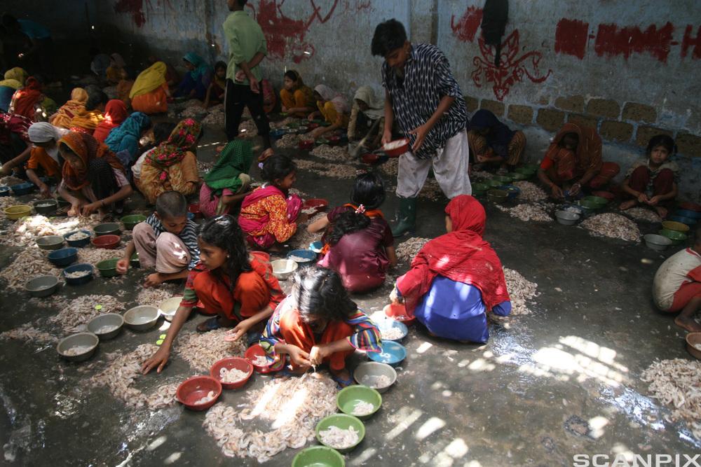 Barn i fargerike klær sitter på gulvet. Foto.
