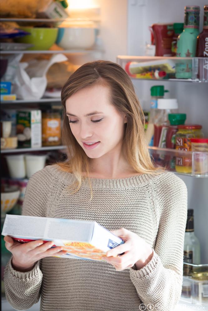 Ei ung dame som les på ingredienslista på ei matvare i ein butikk. Foto.