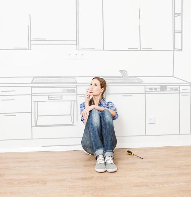 Kvinne sitter på gulvet foran et tegnet kjøkken og ser drømmende ut i lufta. Illustrasjon.