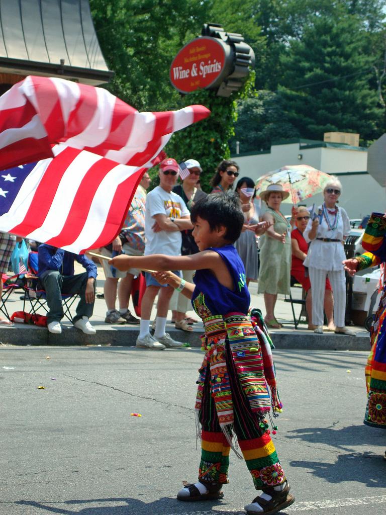 Child holding the American flag on 4th July. Photo.