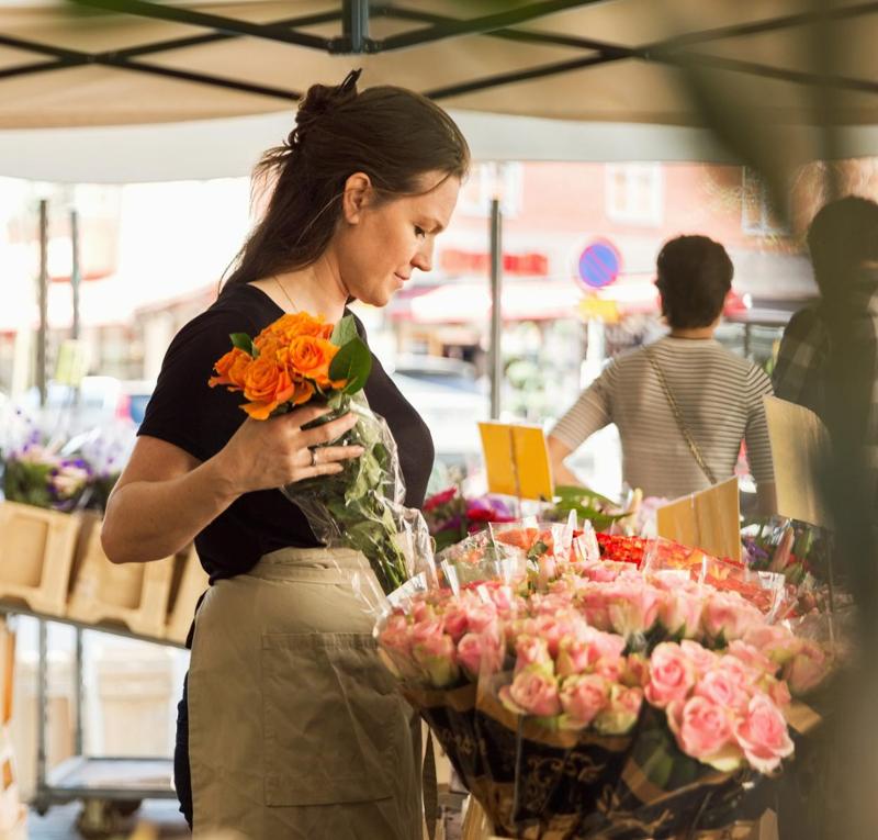 Ung kvinne setter på plass en bukett med roser. Foto.