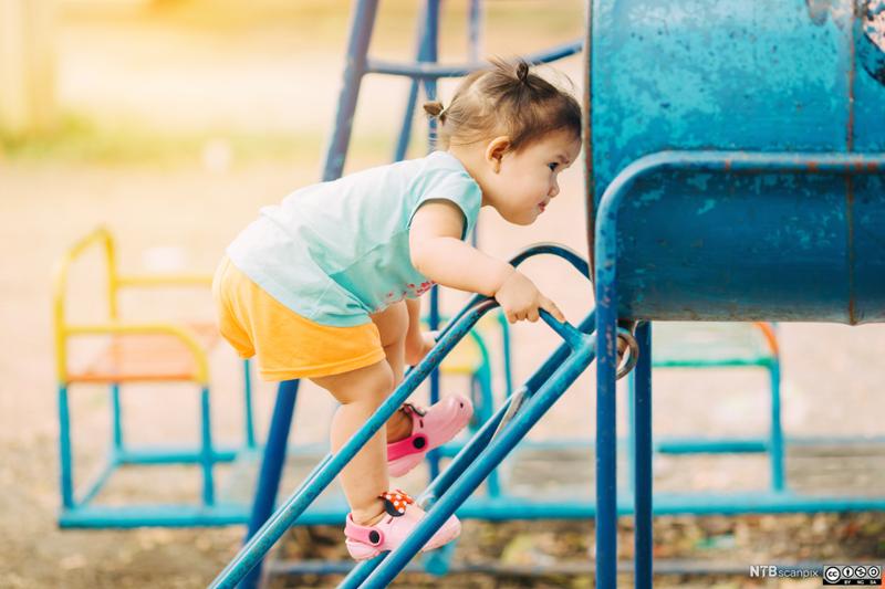 En liten jente øver på ferdighetene sine i en lekepark. Foto.
