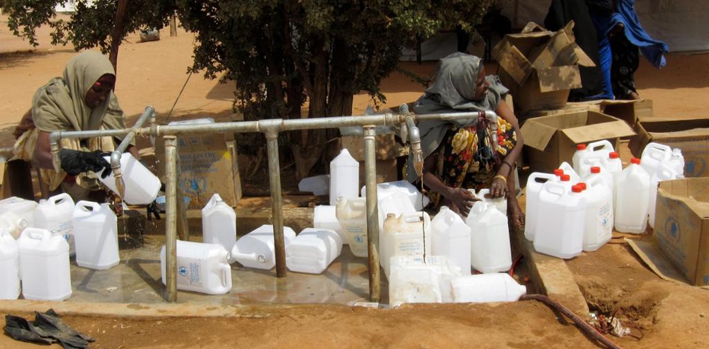 Two women are collecting drinking water in a refugee camp on the Kenyan-Somali border