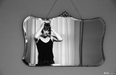 Kvinne som ser seg selv i speilet. Foto. 