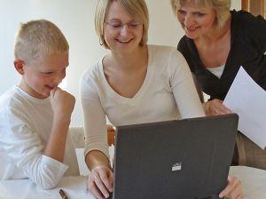 Tre personar ser på PC saman. Foto.