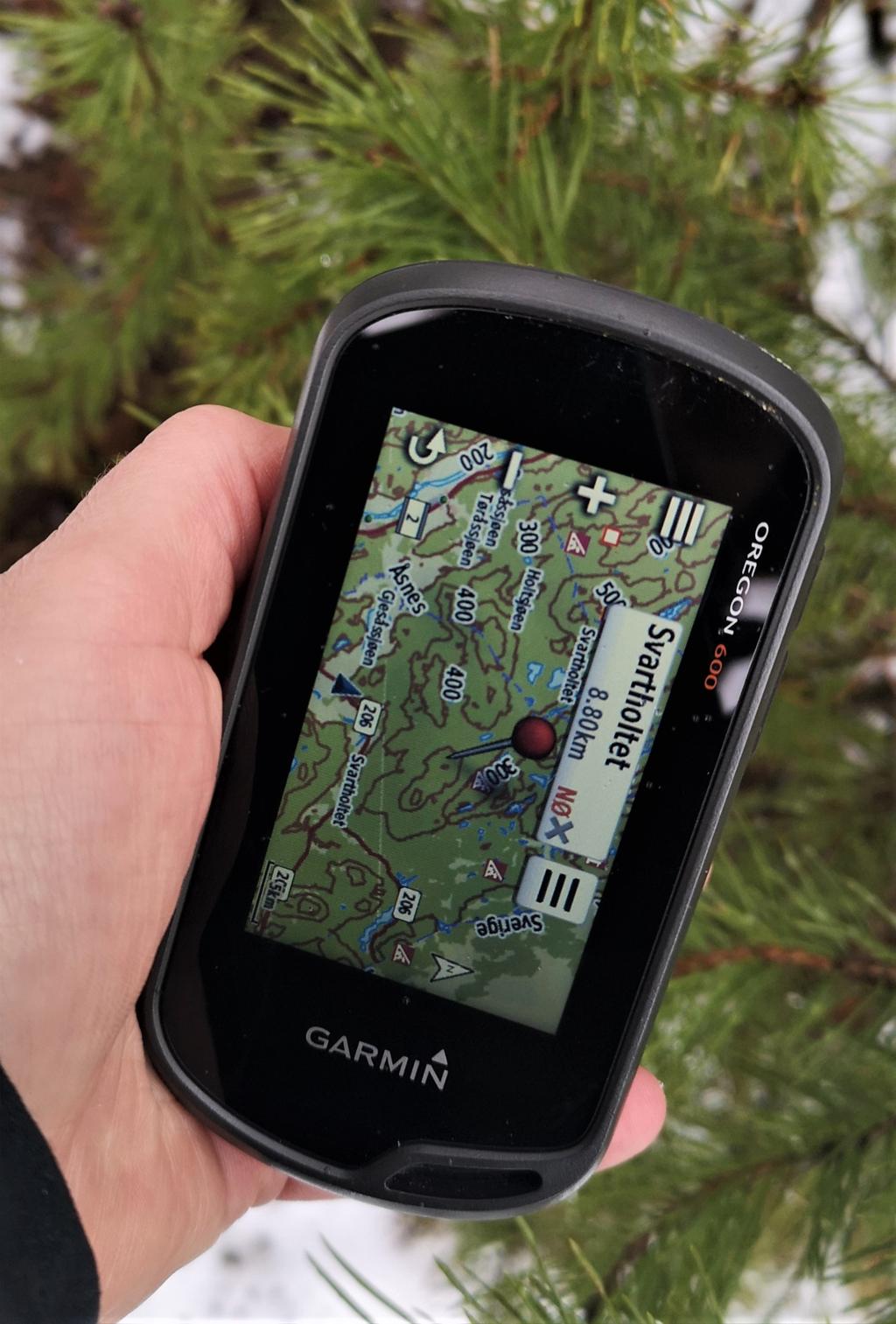 Hånd som holder en GPS-mottaker med kart på skjermen. Foto.