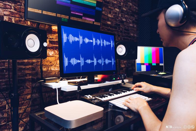  Ung mann gjør etterarbeid på lyd i studio. Bilde.